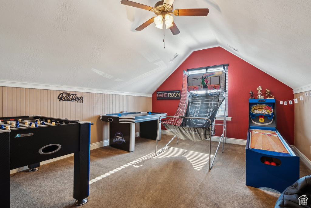 Recreation room featuring vaulted ceiling, carpet flooring, ceiling fan, and a textured ceiling