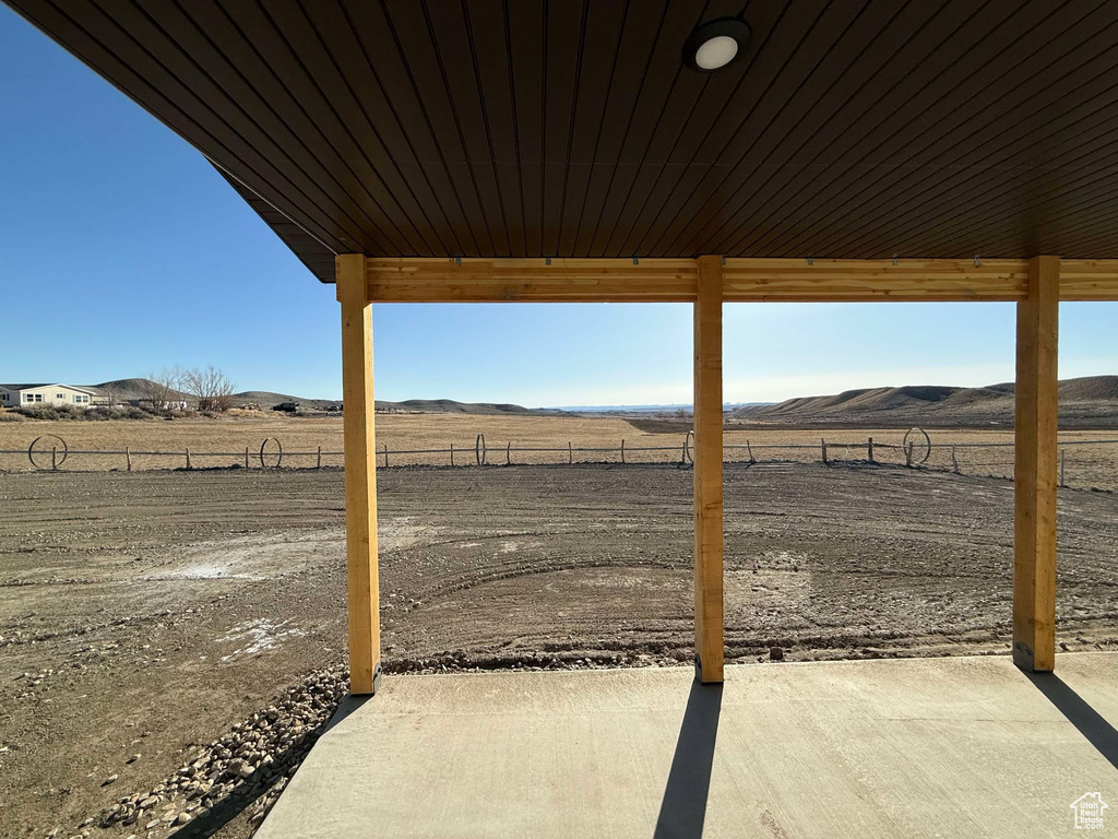 View of yard featuring a rural view, a patio, fence, and a mountain view