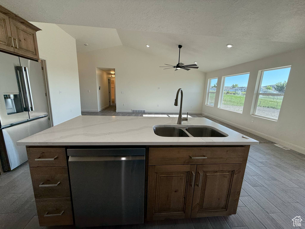 Kitchen featuring appliances with stainless steel finishes, a sink, a ceiling fan, a textured ceiling, and open floor plan