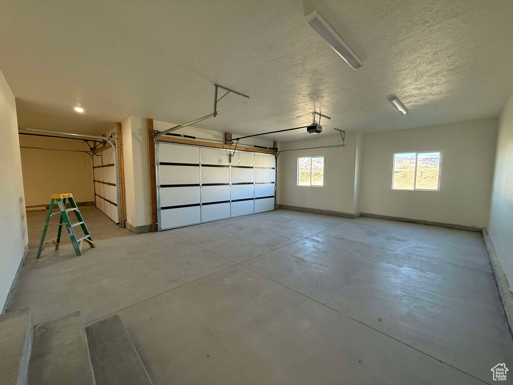 Garage featuring baseboards and a garage door opener