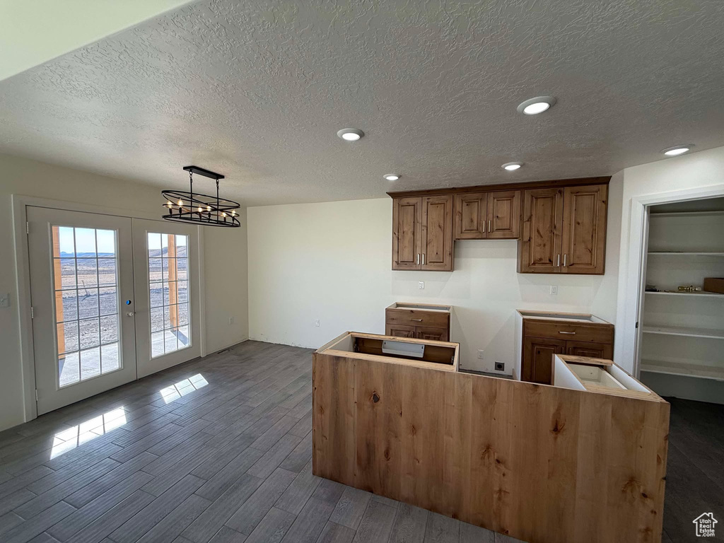 Kitchen with dark wood finished floors, french doors, brown cabinets, and a textured ceiling