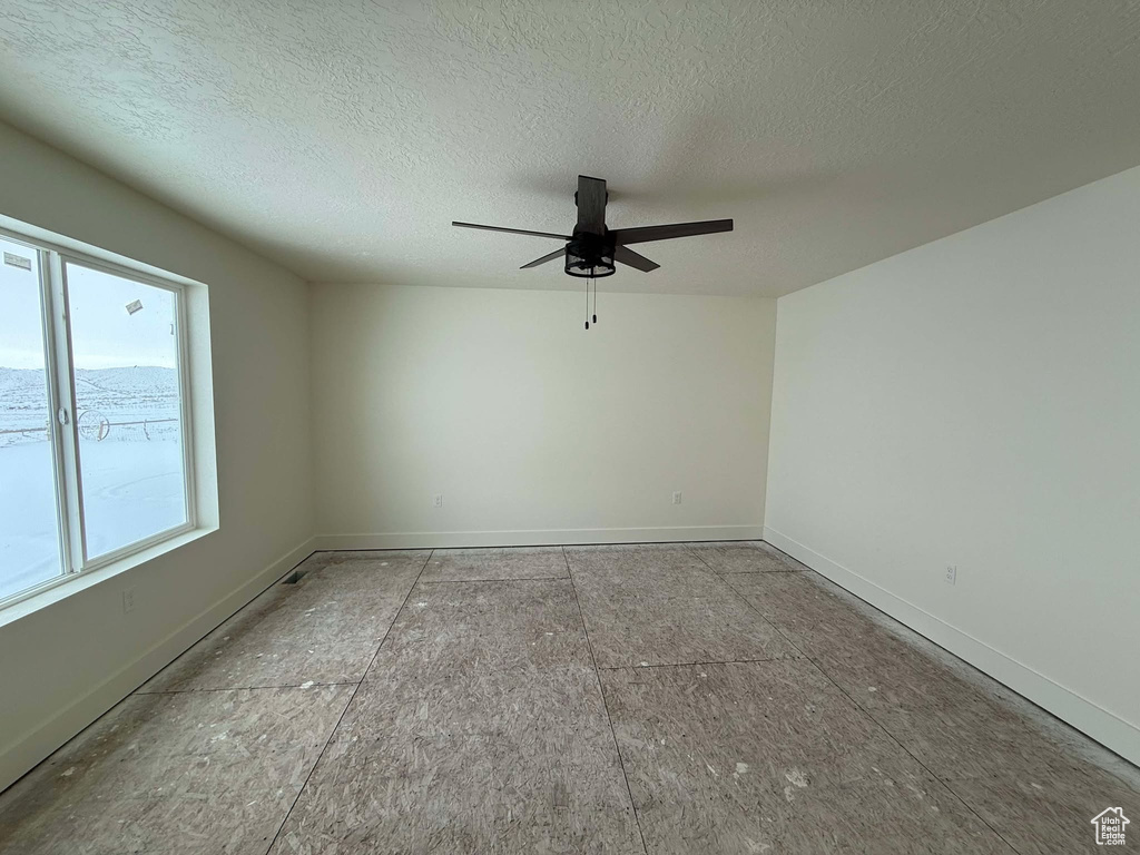 Unfurnished room featuring ceiling fan and a textured ceiling