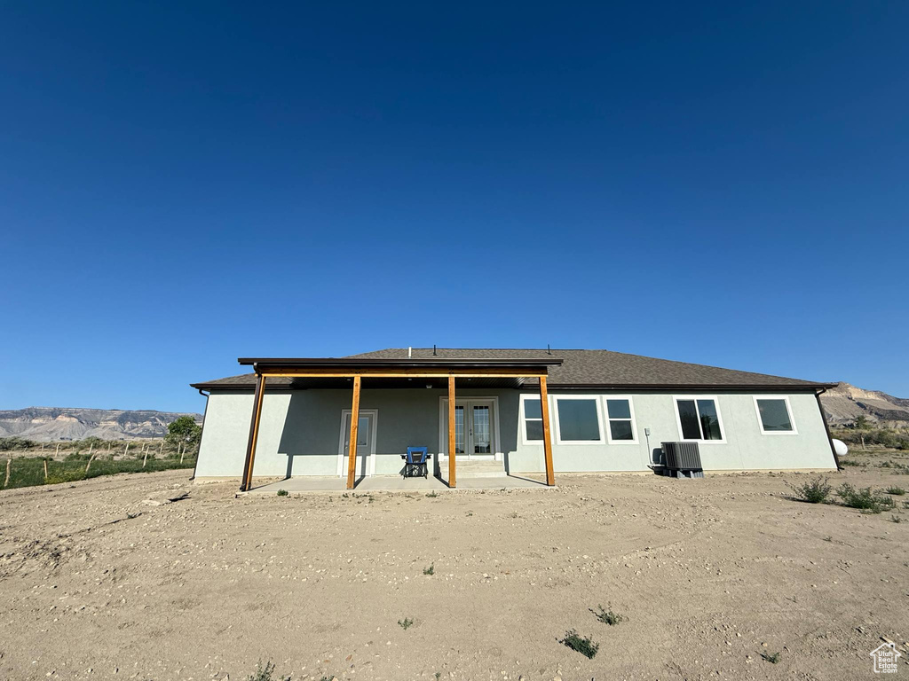 Back of property featuring central AC unit, a patio area, and a mountain view