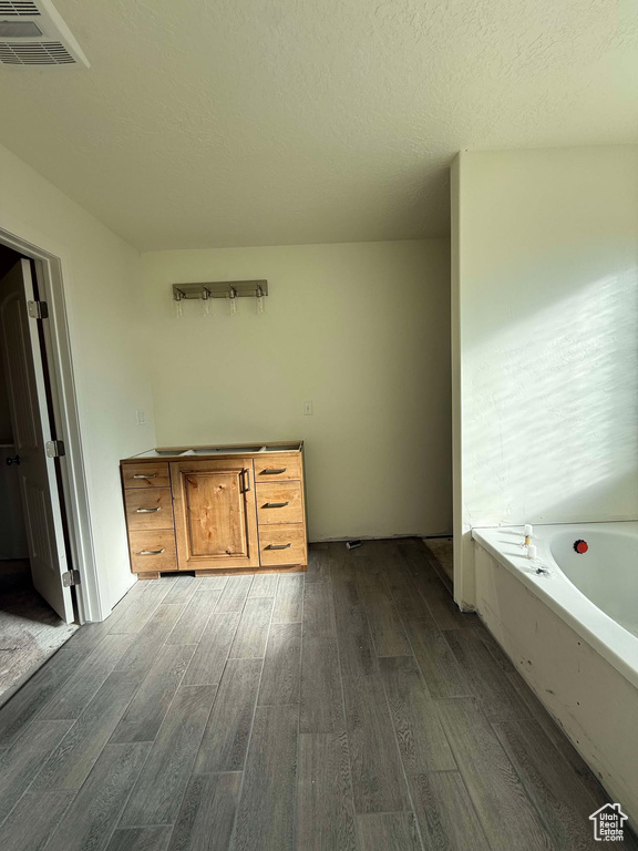 Full bath featuring visible vents, a textured ceiling, a garden tub, and wood finished floors