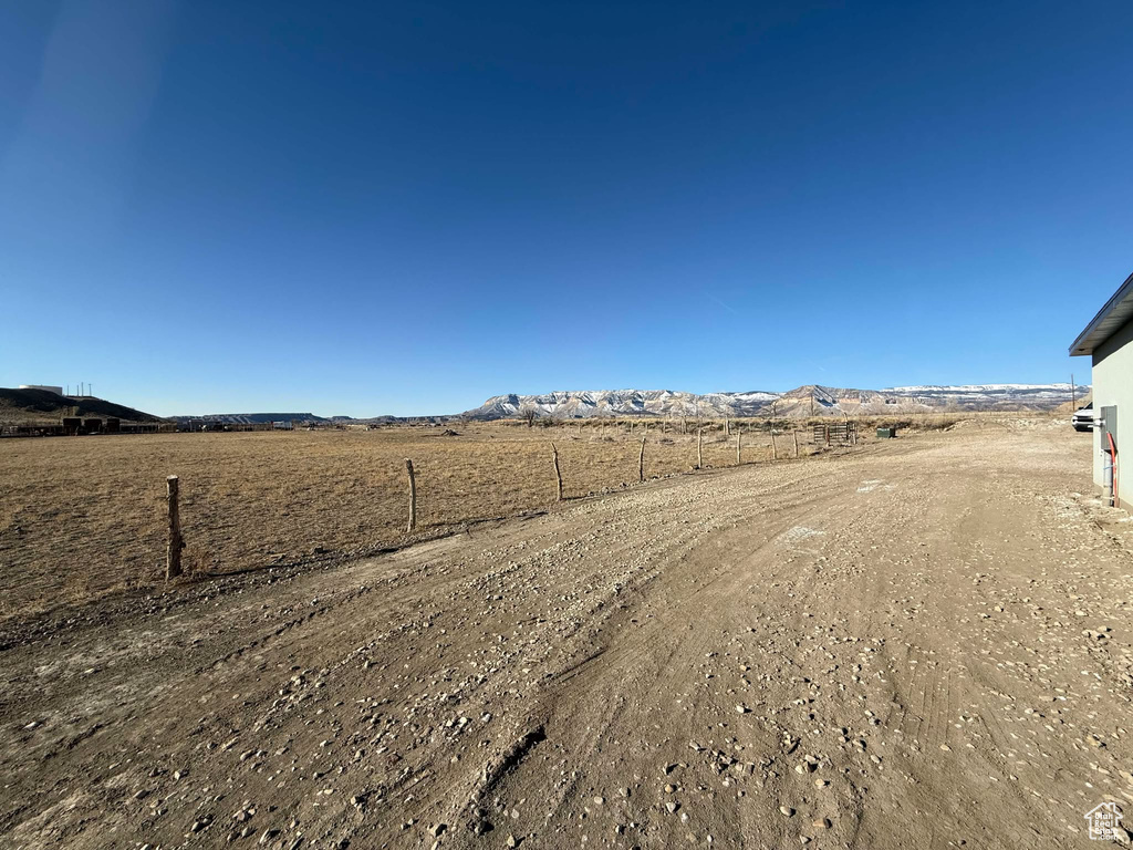 View of yard with a rural view, fence, and a mountain view