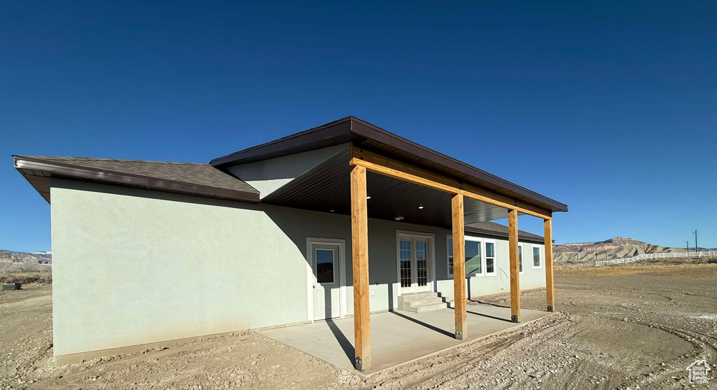 Exterior space with stucco siding, a patio area, a mountain view, and entry steps