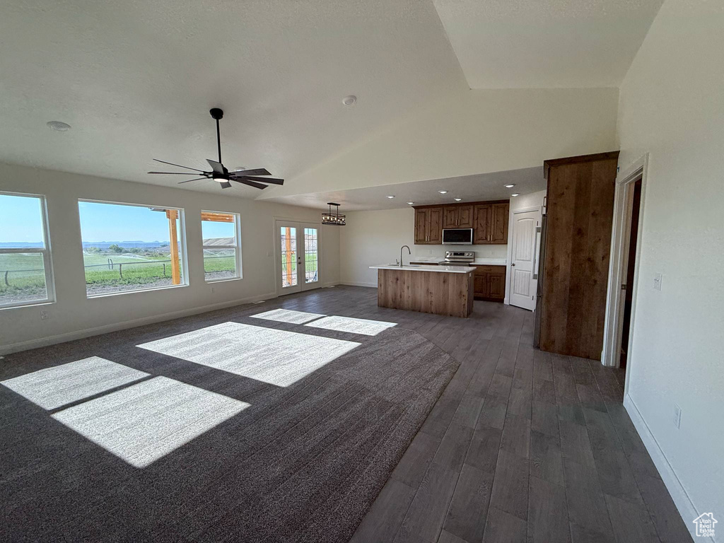 Unfurnished living room with dark wood-style flooring, baseboards, a ceiling fan, and high vaulted ceiling