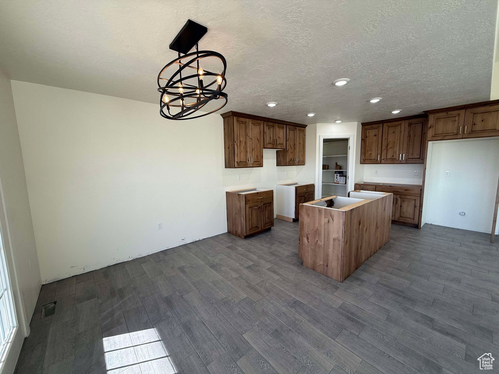 Kitchen featuring visible vents, a kitchen island, pendant lighting, a textured ceiling, and dark wood-style flooring