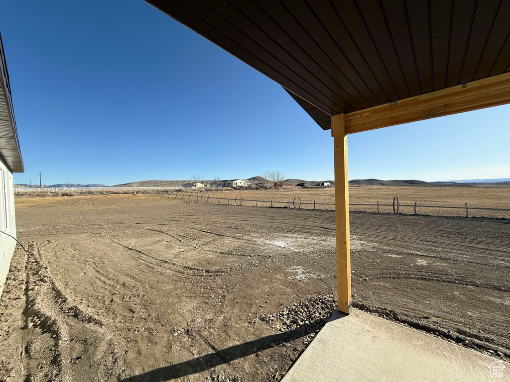 View of yard with a rural view, a mountain view, and fence