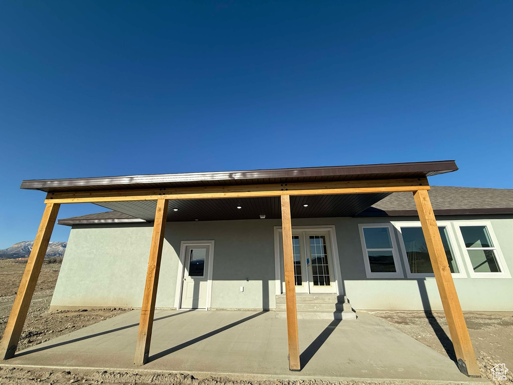 Back of property with a shingled roof, a patio area, french doors, and stucco siding