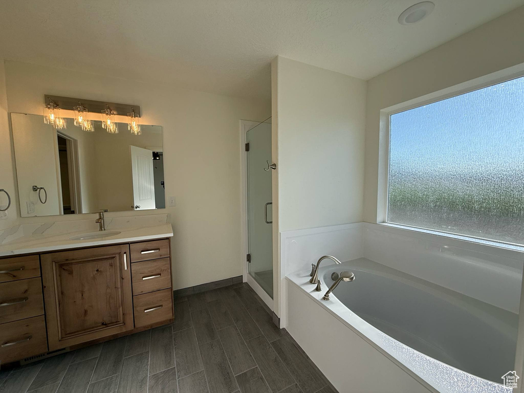 Full bathroom with vanity, a garden tub, a stall shower, wood tiled floors, and baseboards