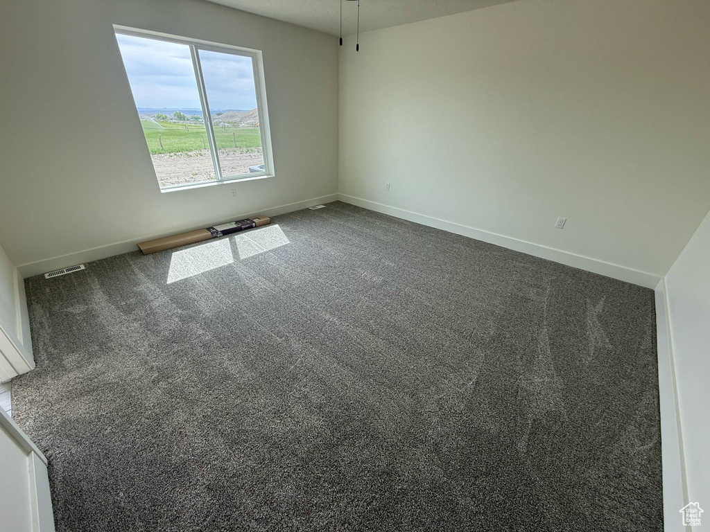 Unfurnished room with baseboards and dark colored carpet