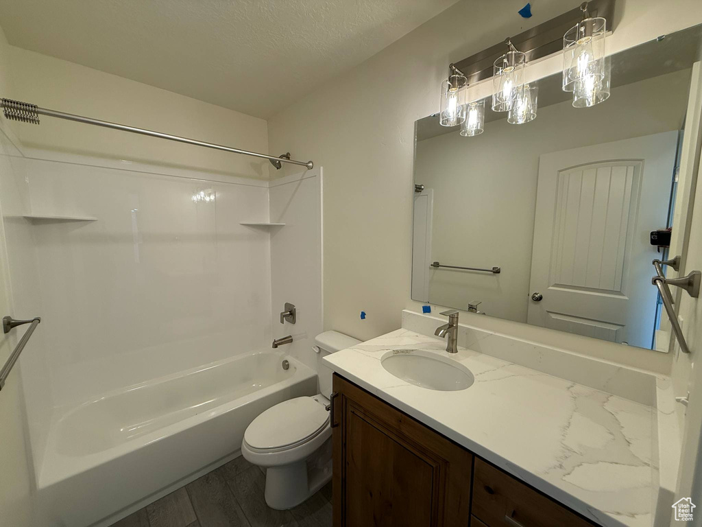 Bathroom featuring wood finished floors, toilet, vanity, and shower / bath combination
