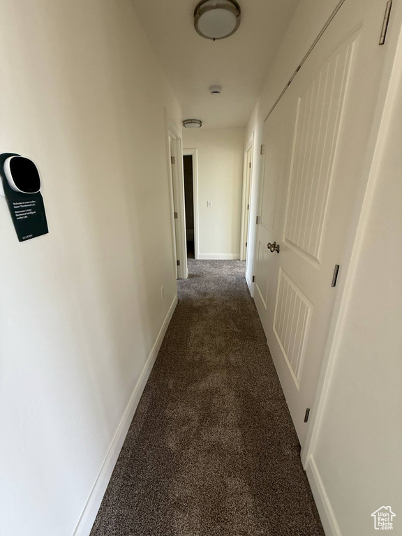 Hallway with dark carpet and baseboards