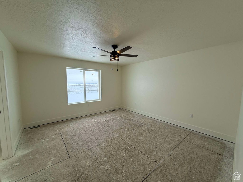 Unfurnished room featuring ceiling fan and a textured ceiling