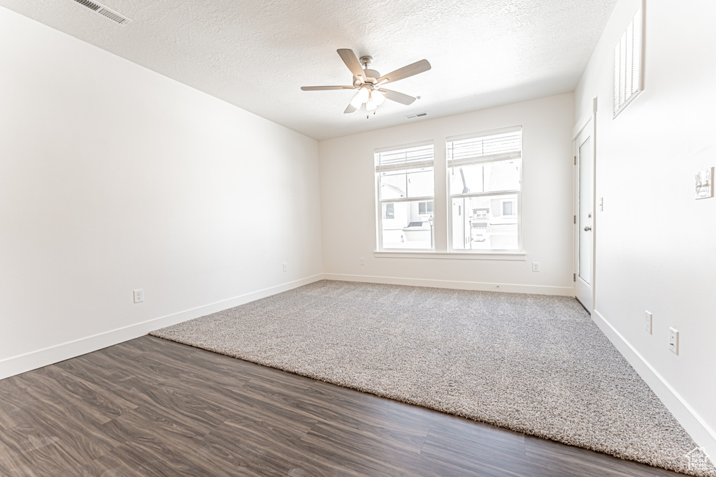 Spare room with a ceiling fan, a textured ceiling, baseboards, and wood finished floors