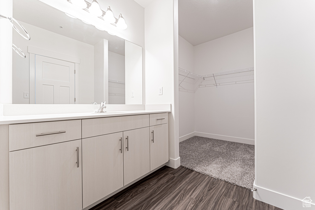 Bathroom with vanity, wood finished floors, a spacious closet, and baseboards