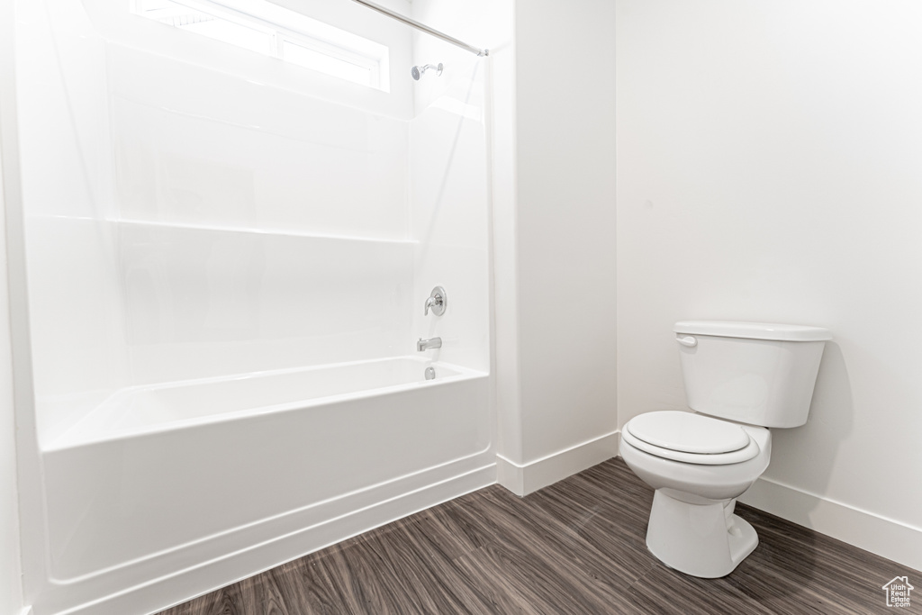 Full bathroom with baseboards, toilet, tub / shower combination, and wood finished floors