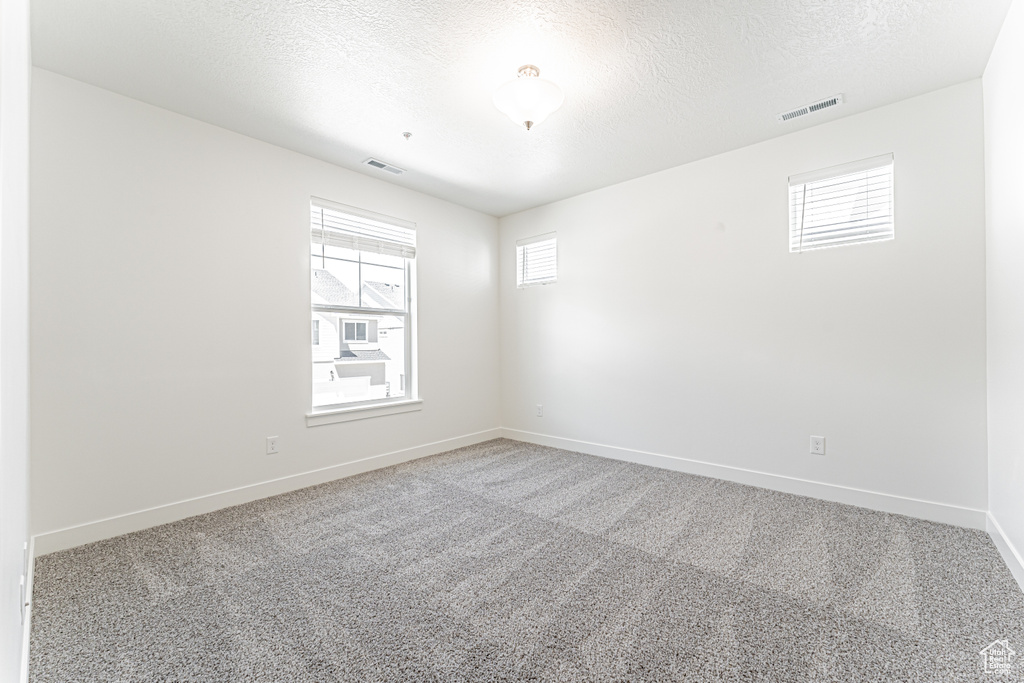 Unfurnished room with carpet floors, baseboards, and a textured ceiling