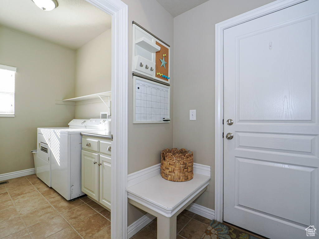 Washroom featuring light tile patterned floors, cabinets, and washer and clothes dryer