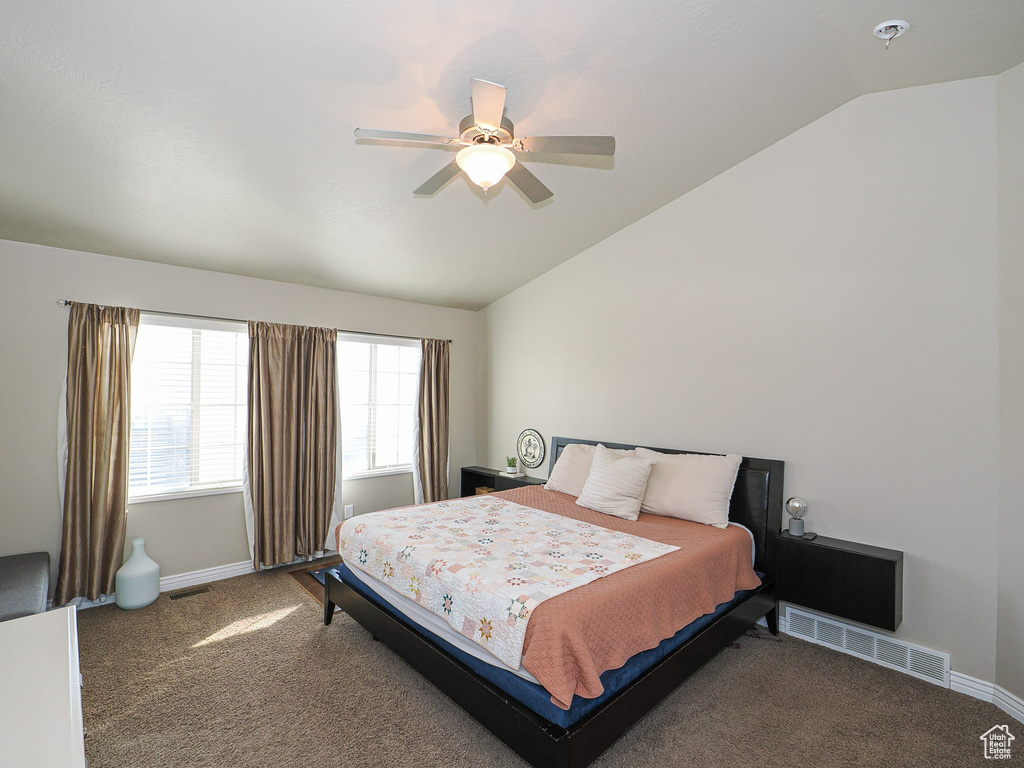 Bedroom with ceiling fan, lofted ceiling, and dark colored carpet