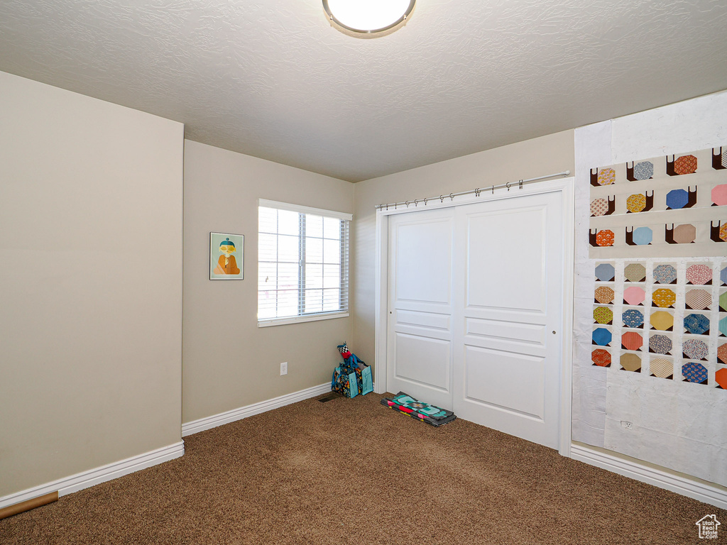 Recreation room featuring a textured ceiling and carpet flooring