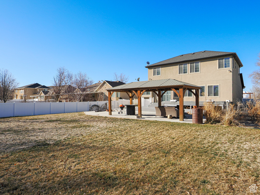 Rear view of property with a lawn, a gazebo, and a patio