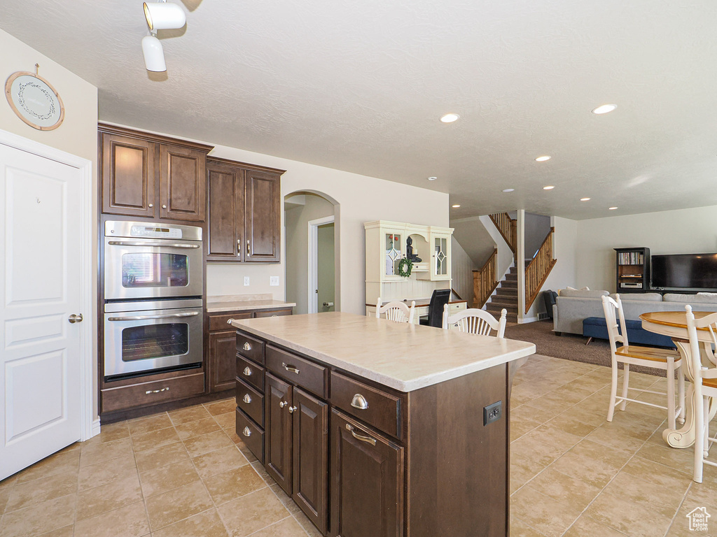 Kitchen featuring dark brown cabinets, a kitchen island, and double oven