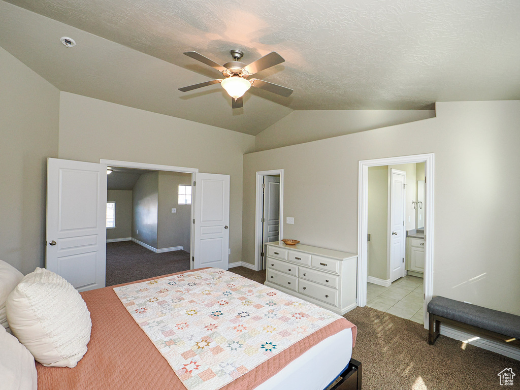 Bedroom featuring a textured ceiling, lofted ceiling, light carpet, ceiling fan, and ensuite bathroom