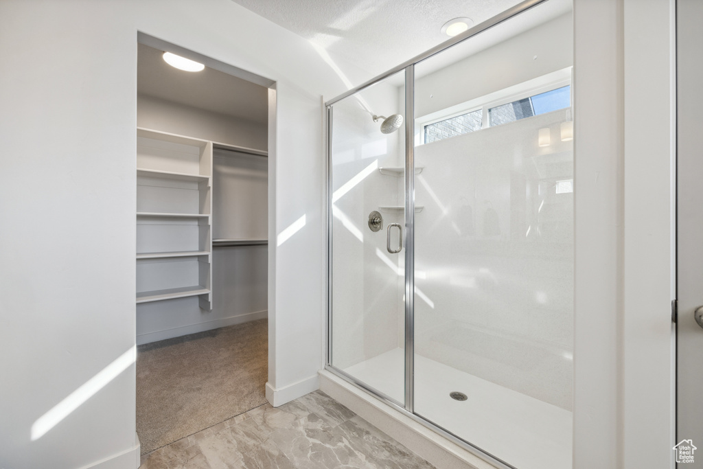 Full bathroom featuring a shower stall, a spacious closet, and baseboards