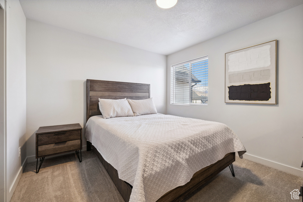 Bedroom with light colored carpet, a textured ceiling, and baseboards