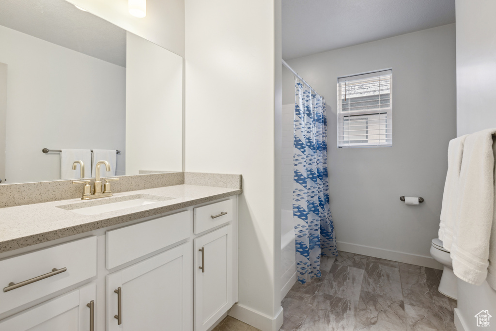 Full bathroom featuring marble finish floor, curtained shower, toilet, vanity, and baseboards
