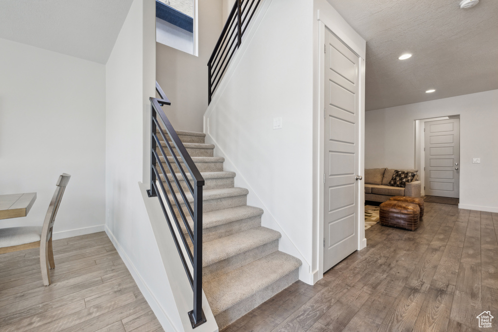 Staircase featuring recessed lighting, baseboards, and wood finished floors