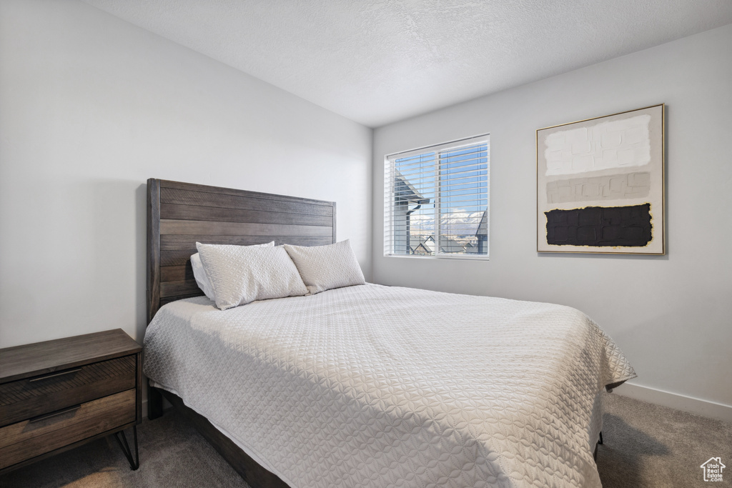 Bedroom featuring a textured ceiling, carpet, and baseboards