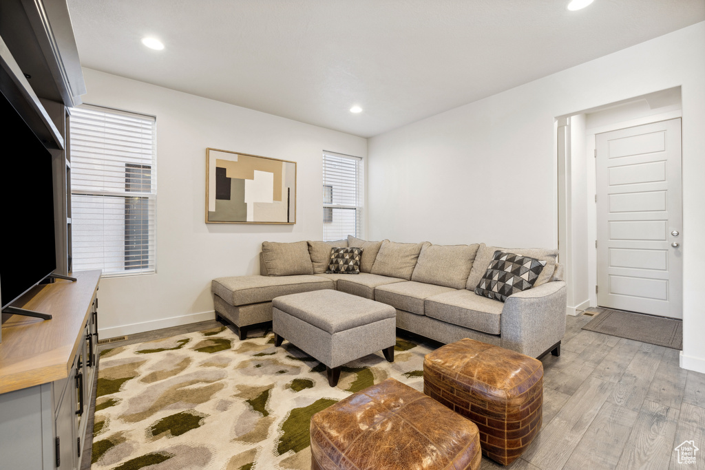 Living area with baseboards, recessed lighting, and light wood-style floors