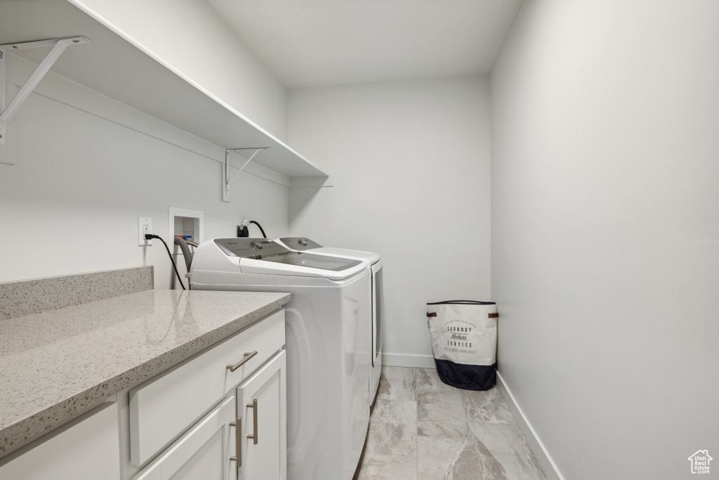 Washroom with marble finish floor, washing machine and dryer, and baseboards