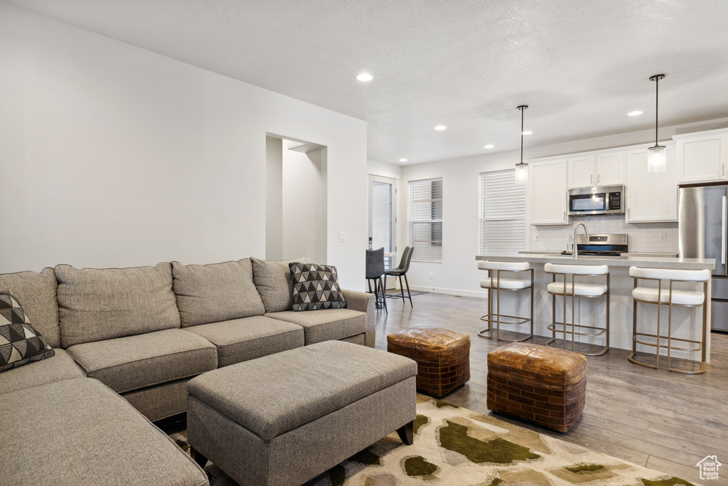 Living area with baseboards, light wood-style flooring, and recessed lighting