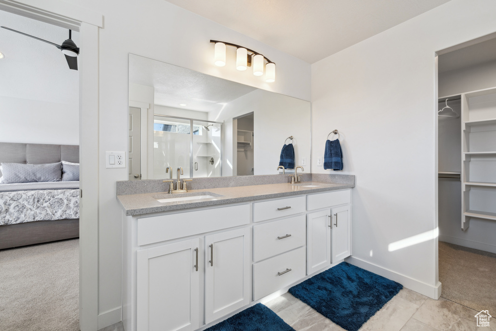 Full bathroom featuring ensuite bathroom, double vanity, a sink, and a walk in closet