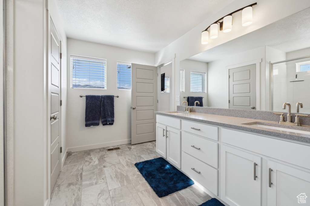 Bathroom featuring baseboards, double vanity, a sink, and a shower stall