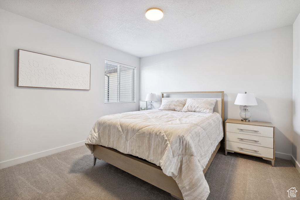 Bedroom with a textured ceiling, carpet, and baseboards