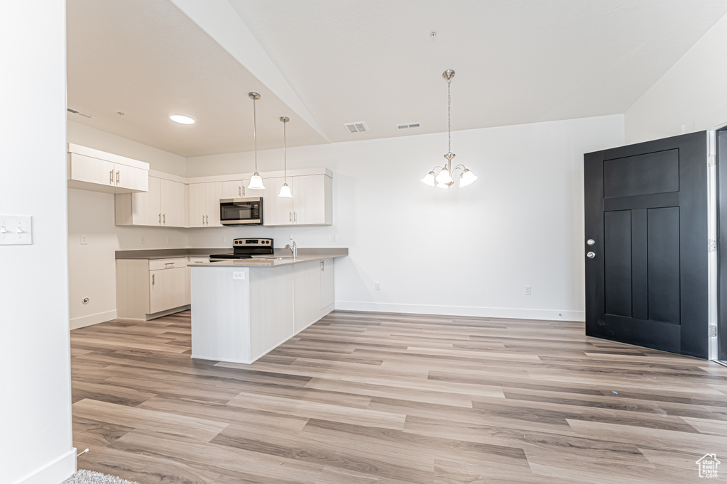 Kitchen with appliances with stainless steel finishes, a peninsula, baseboards, light wood-type flooring, and white cabinets