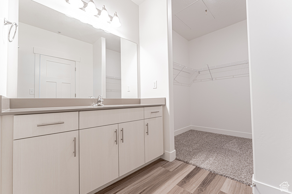 Bathroom with vanity, wood finished floors, a spacious closet, and baseboards
