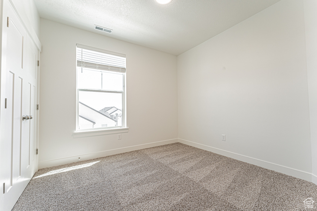 Unfurnished room featuring carpet flooring, a textured ceiling, and baseboards