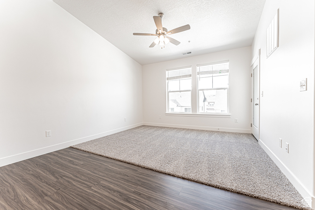 Empty room featuring ceiling fan, a textured ceiling, baseboards, and wood finished floors