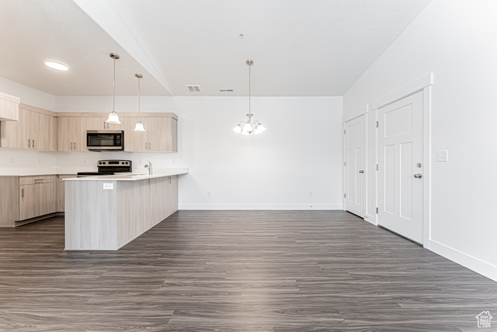 Kitchen with light brown cabinets, appliances with stainless steel finishes, a peninsula, and baseboards