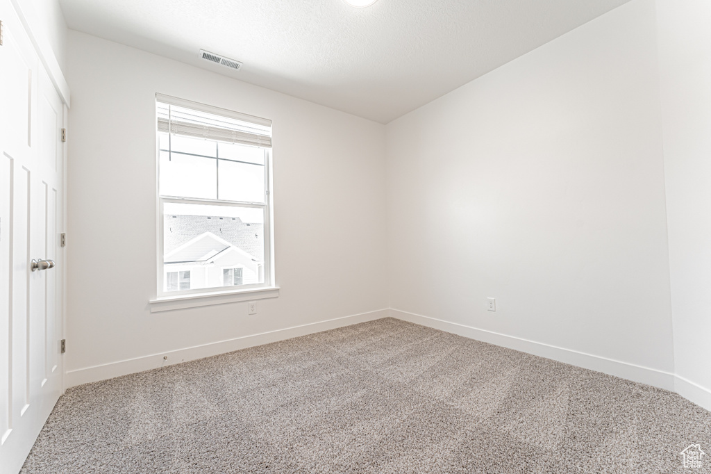 Carpeted spare room featuring baseboards