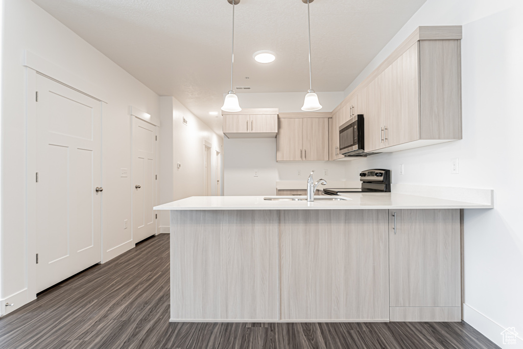 Kitchen with stainless steel appliances, a peninsula, baseboards, a sink, and light countertops