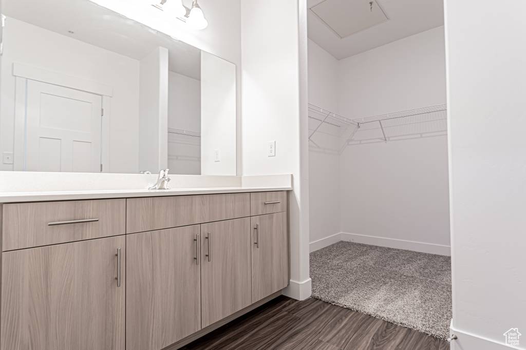 Bathroom featuring vanity, wood finished floors, baseboards, and a walk in closet
