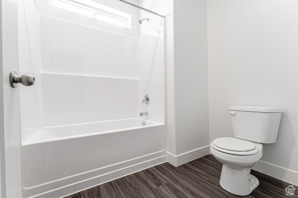 Full bathroom with baseboards, toilet, bathtub / shower combination, and wood finished floors