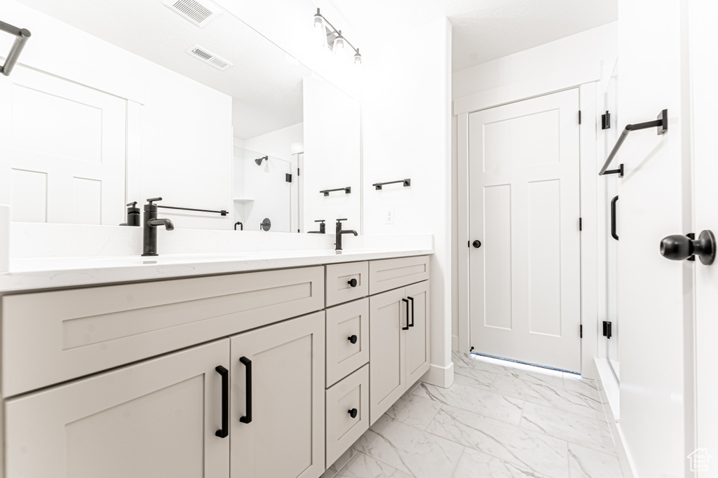 Bathroom featuring double vanity, a stall shower, visible vents, and marble finish floor